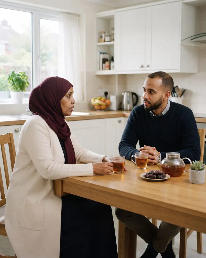 A mother and her adult son talking quietly over tea at their kitchen table