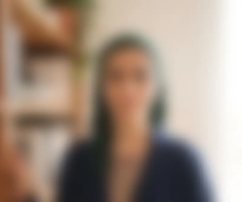 A Muslim woman in a green headscarf standing by a bookshelf, shown blurred, as an example of a private profile photo